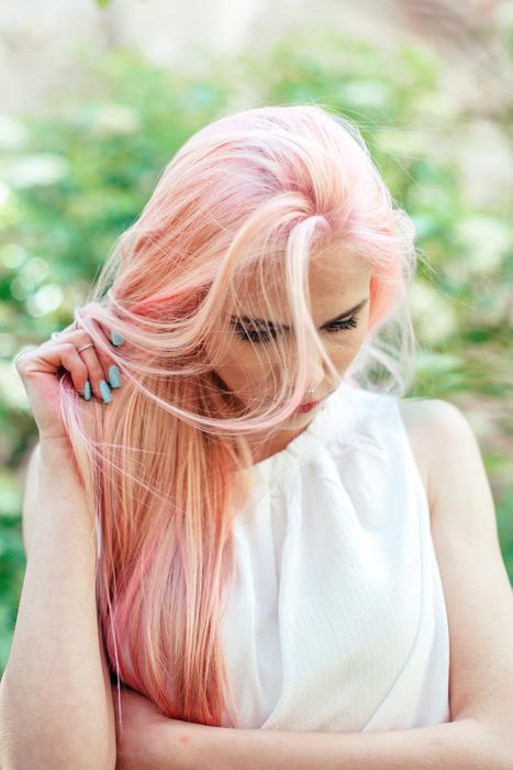 Woman with pink hair on green blurred background with the plants