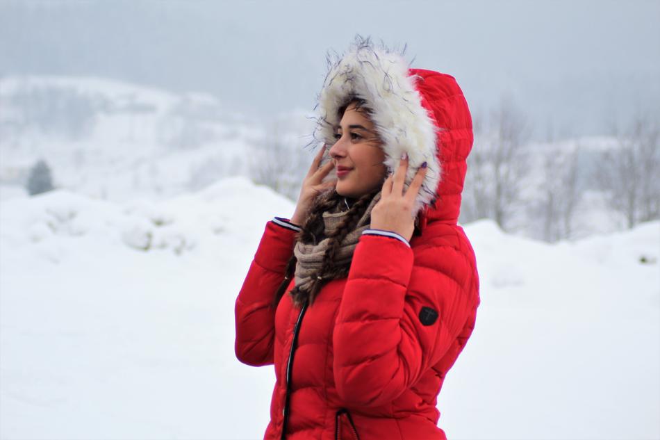 pretty young girl in red jacket at snowy winter