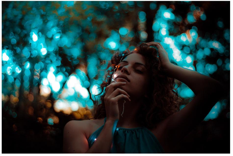 Portrait of the beautiful girl with curly hair and in blue dress, among the beautiful forest in blue light
