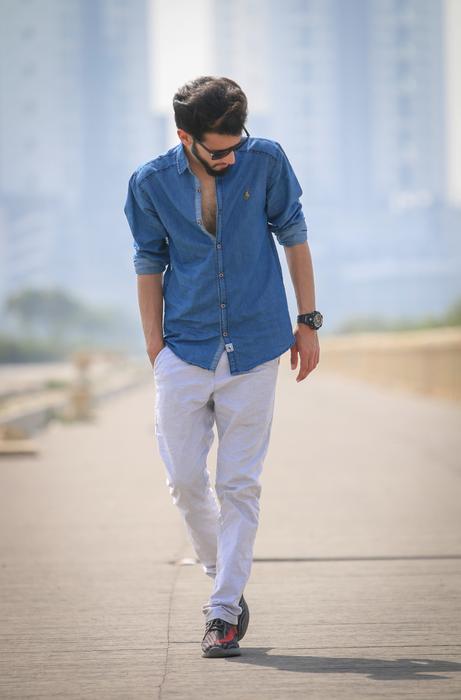 photo of a young man in a denim shirt walking along the road