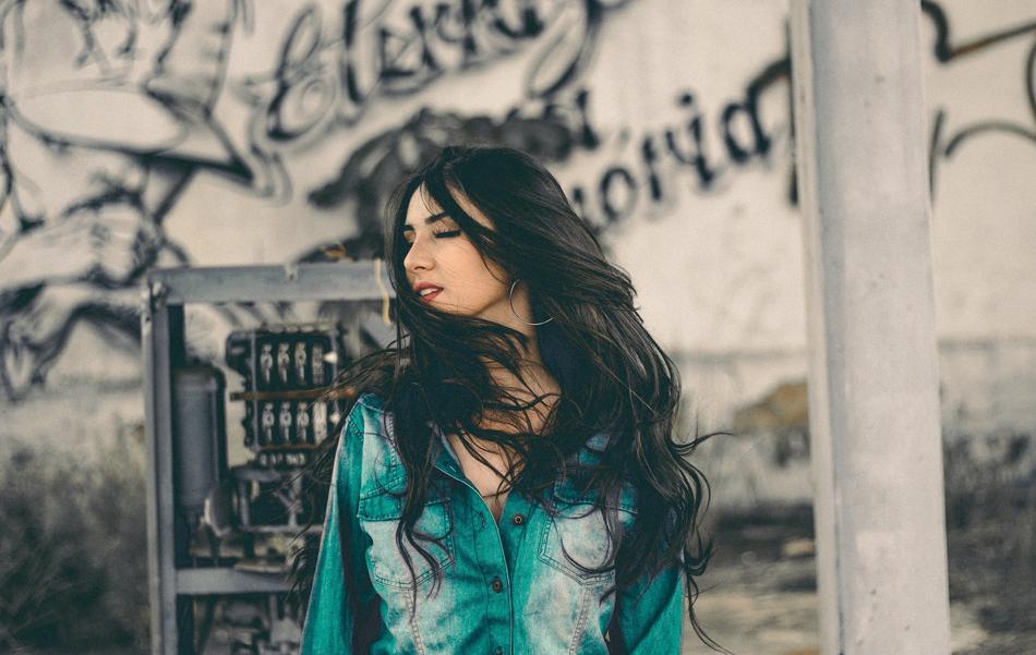 Woman with the black hair posing near the wall with graffiti