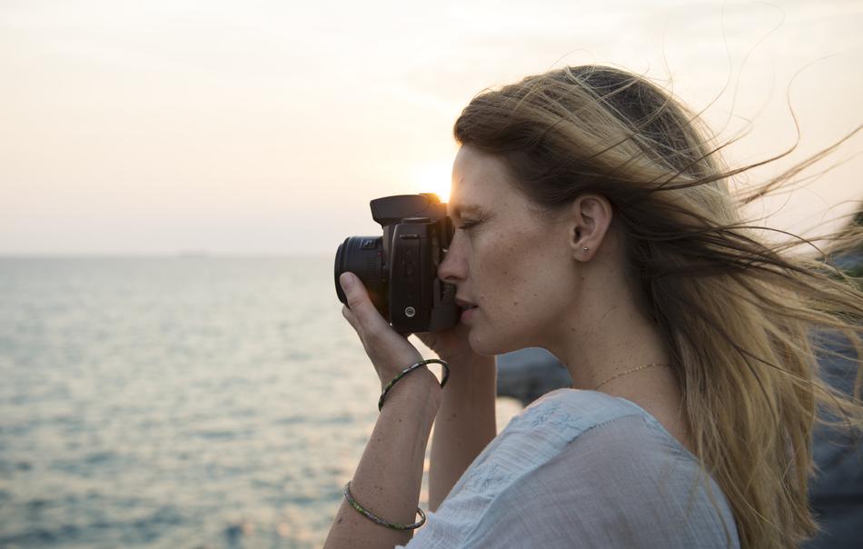 girl with a camera near the water at sunset