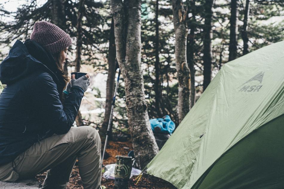 girl sitting near the tent in the forest