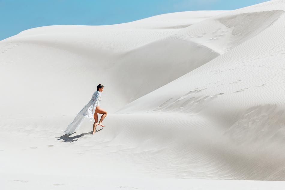 Girl in white clothing walking on beautiful white sand on landscape