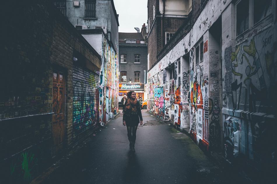 girl on a narrow street among graffiti at dusk