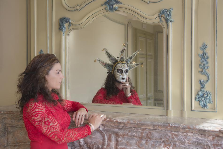 reflection of a girl in a red dress with a mask