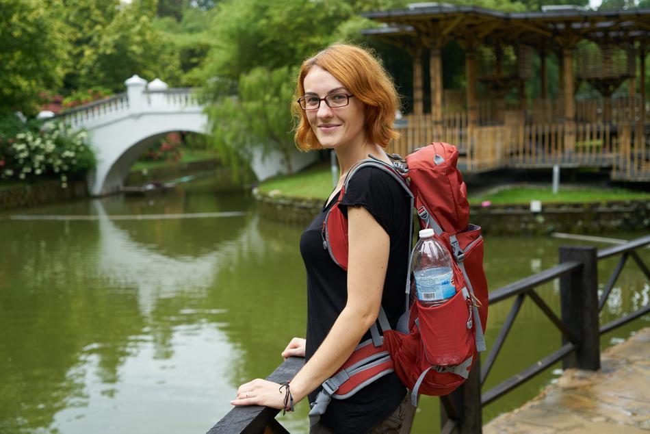 girl with a backpack near the lake in the park