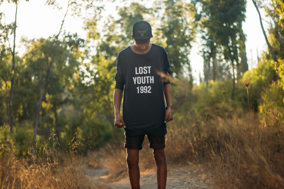 Boy in cap, standing on the path, among the colorful plants in light