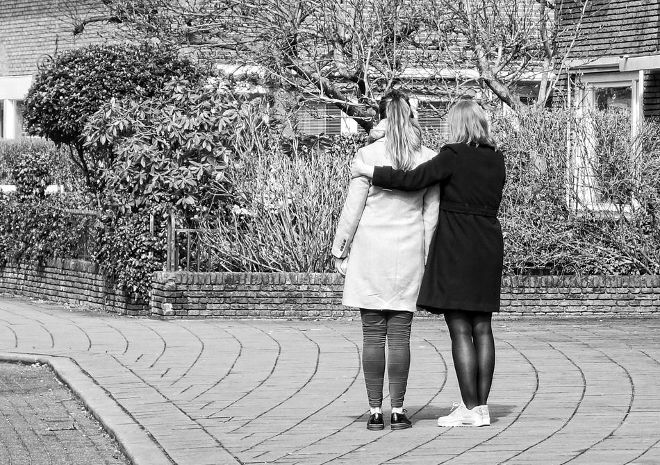 two women stand on the street in black and white background