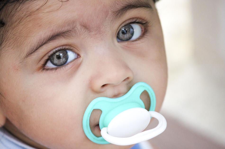 portrait of a little girl with a blue pacifier