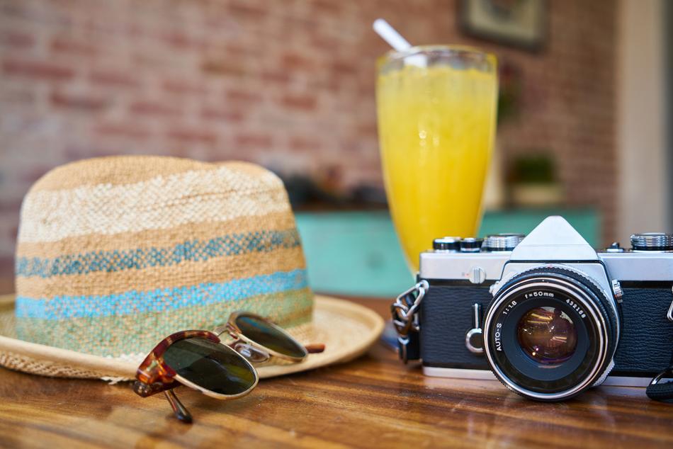 retro camera, hat, sunglasses and chilled juice on the table