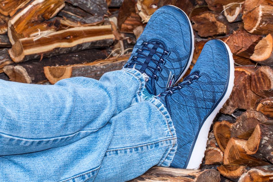 Close-up of the blue shoes on the legs of the person, near the colorful wood