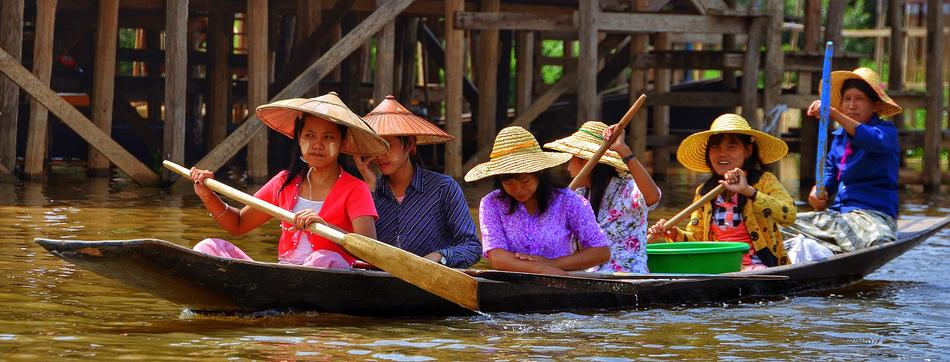 Ladies in colorful clothing, on the boat, among the water, near the wooden construction