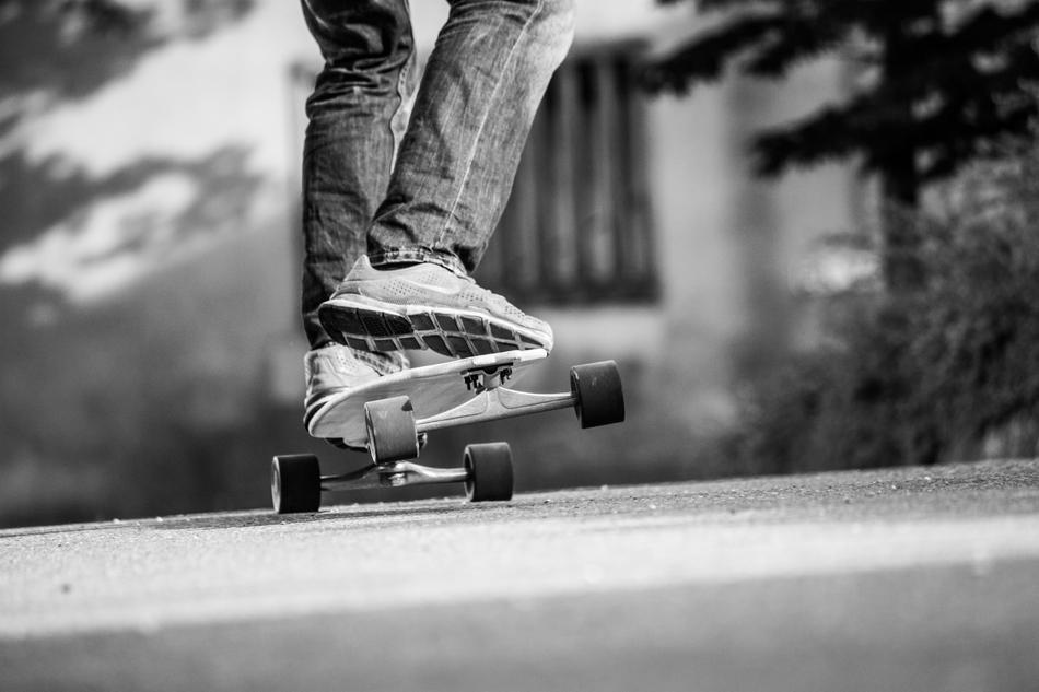 Black and white photo of a man longboarding among the plants