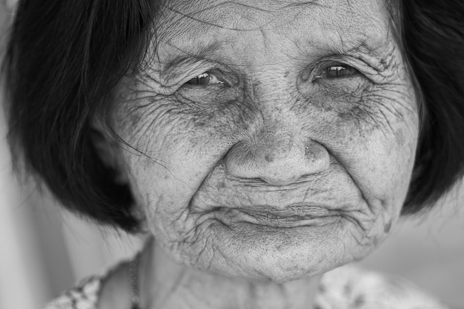 Black and white portrait of the old, tired woman, at blurred background