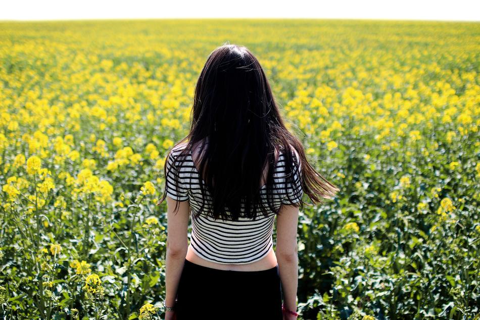 woman looking at a yellow field on a sunny day