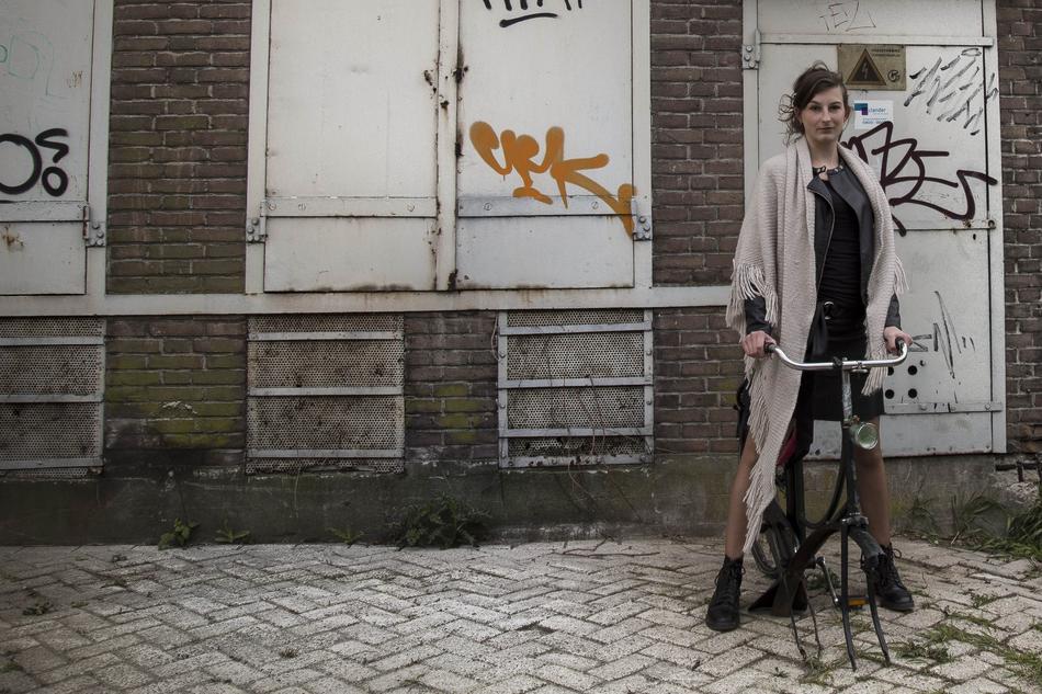 Woman on the old bicycle, near the building, with the colorful graffities