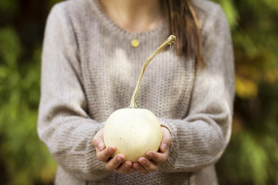 Woman, holding beautiful fruit, in the hands, near the colorful plants
