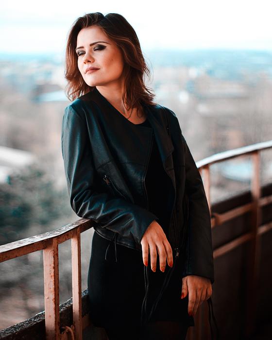 Beautiful, smiling woman with the make-up, and in dress, posing on the railing, at landscape on background