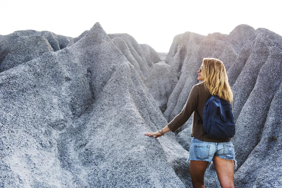 blonde girl with backpack among grey rocks