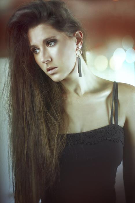 Portrait of the posing woman in black dress, at background with lights
