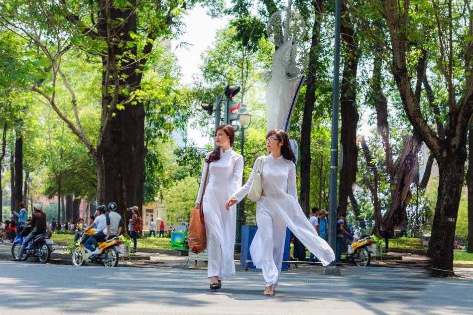 Girls in white, long coats, walking in the beautiful park in Ho Chi Minh, Vietnam