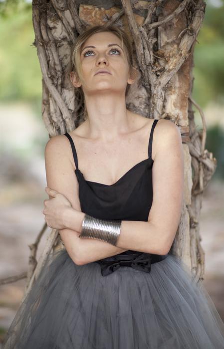 Blonde woman in dress, with the bracelet, posing near the tree, at blurred background