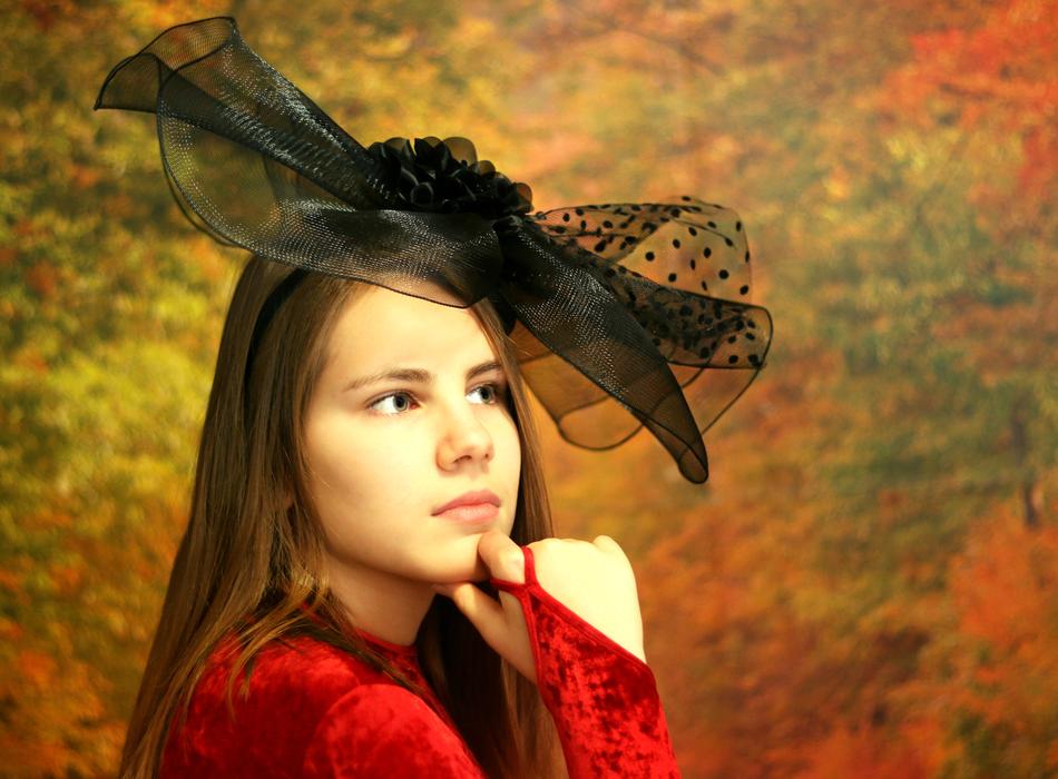 Portrait of the girl in red dress and with black cap, among the beautiful and colorful plants