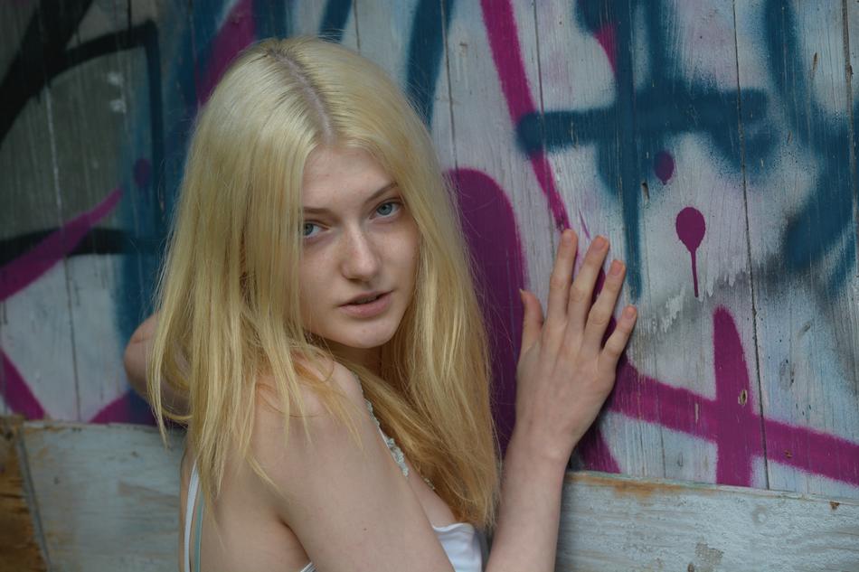 Posing, beautiful, blonde woman near the wall with colorful graffities