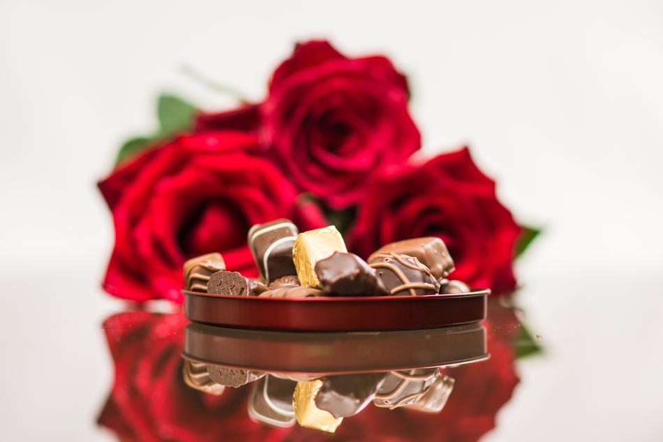 chocolate candies on the background of a bouquet of red roses