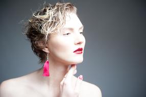 Portrait of the blonde woman, with the red lips and pink earrings, in light