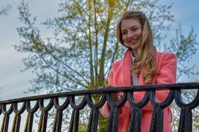 Beautiful, smiling blonde girl on the bridge with black railing