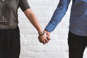couple holding hands on white brick wall background