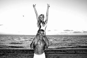 black and white, a girl sits on a guy's shoulders on the beach