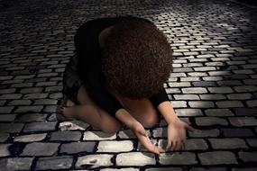 girl with curly hair prays on the pavement
