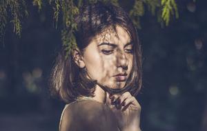 girl posing in the shade of a tree on a blurred background