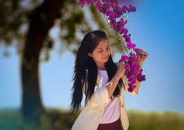 girl with beautiful purple flowers near a tree in a blurry background