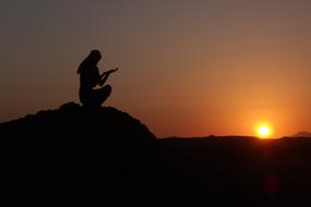 silhouette of a woman in a scarf on a hill at dusk