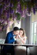 the groom with the bride at the table under purple flowers