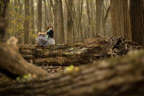 woman sits on log in Forest