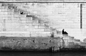 black and white, a woman sits on the steps on the descent on the embankment