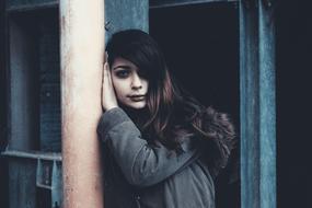 photo of a brunette standing by a pole