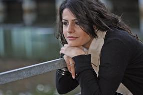Portrait of the smiling woman, posing on the railing, at blurred background