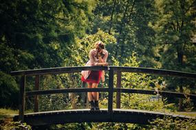 Woman, posing on the bridge, among the green and yellow plants, in the beautiful forest