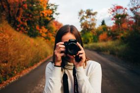 girl with a camera on the road on a blurred background
