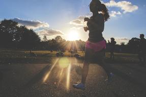 Woman, jogging on the path, among the colorful plants, in sunlight