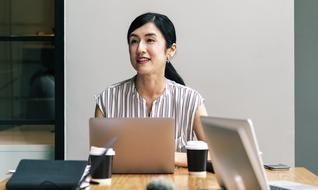 Portrait of a smiling woman, at the workplace with laptops and other stuff