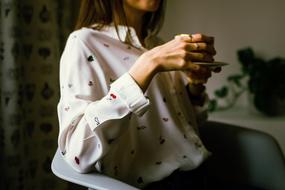 girl in a white blouse drinks coffee