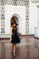 stylish girl in black outfit posing at white building