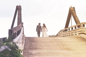 monochrome photo of newlyweds walking on the bridge